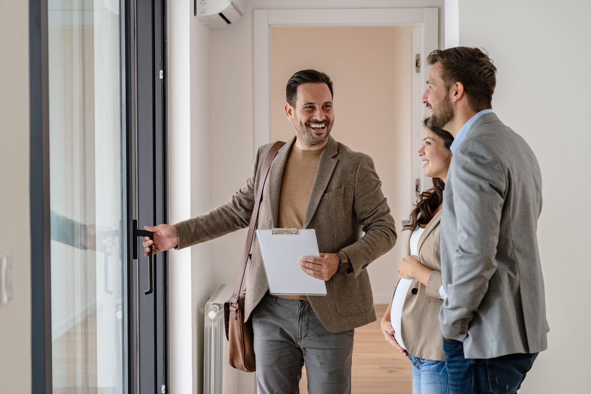 Young married couple talking with a real-estate agent visiting apartment for sale or for rent